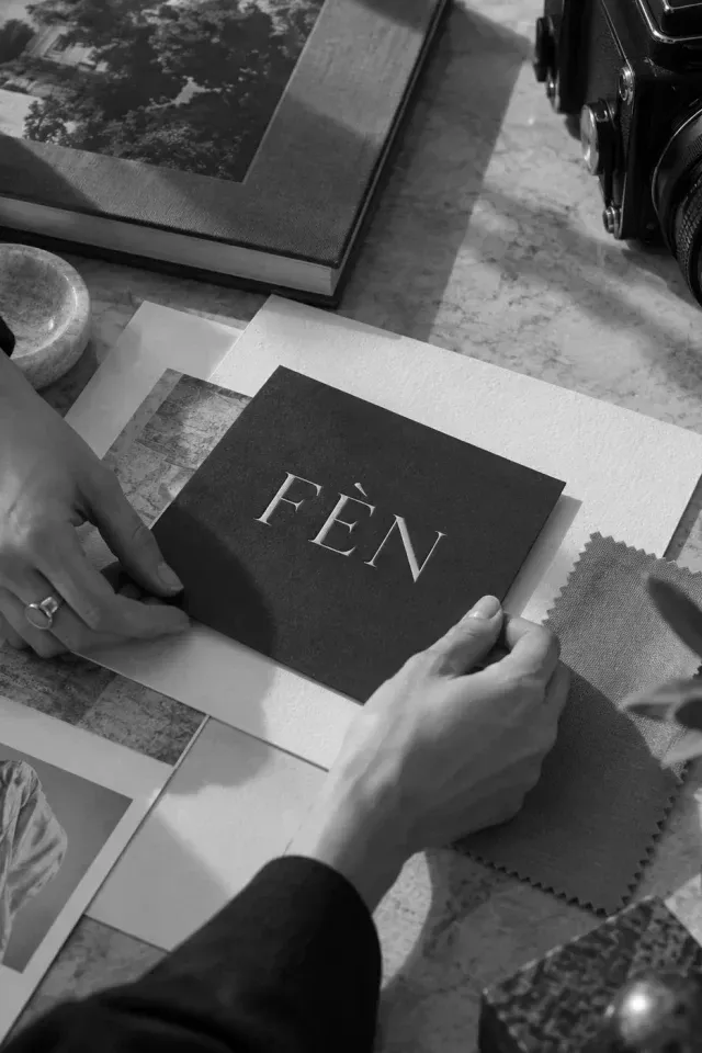 Handen op een tafel vol FÈN-drukwerk en materiaalstalen